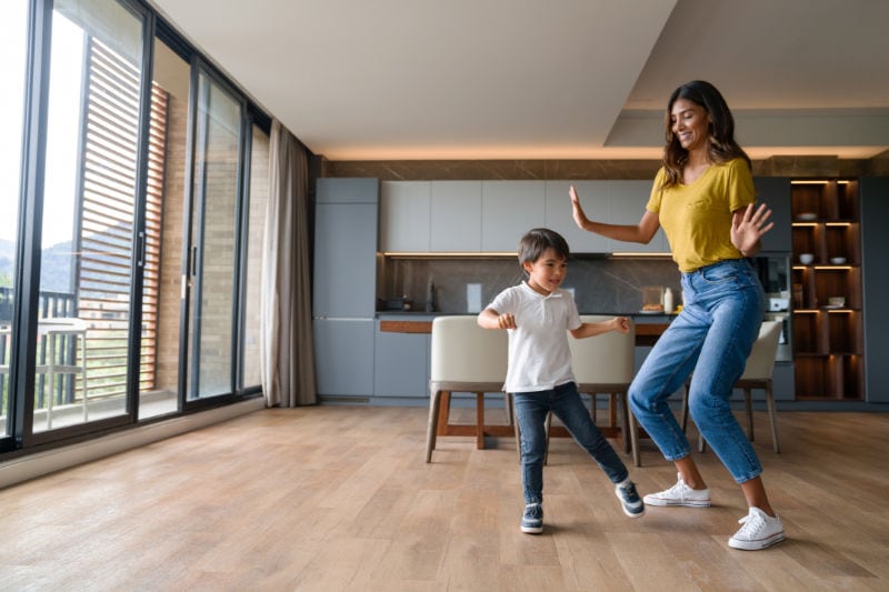 Woman and son happily dancing indoors. High Efficiency HVAC and Water Heaters