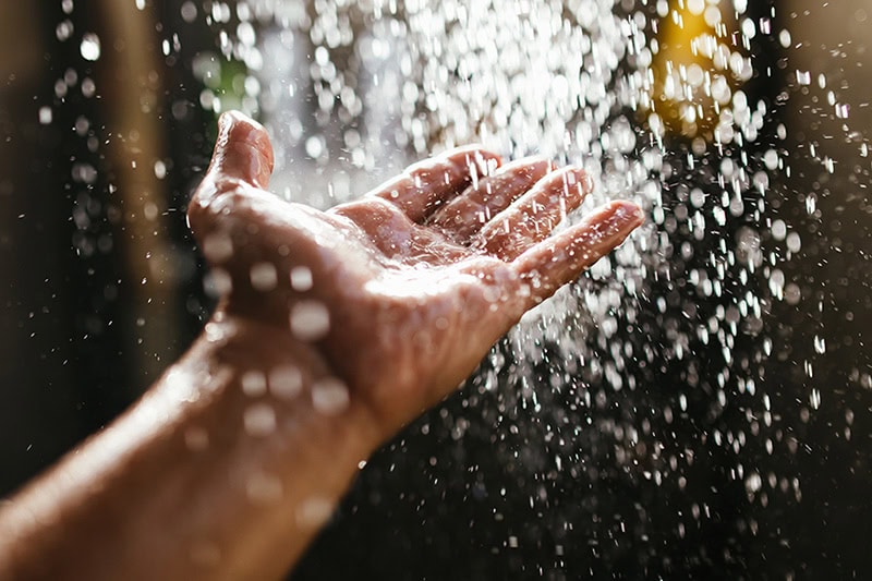 Get Space-Saving Comfort with a Combi Boiler on the South Jersey Shore. Photo of a hand under a running shower.