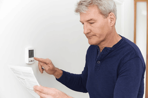 Man reading instructions while programming a residential thermostat.