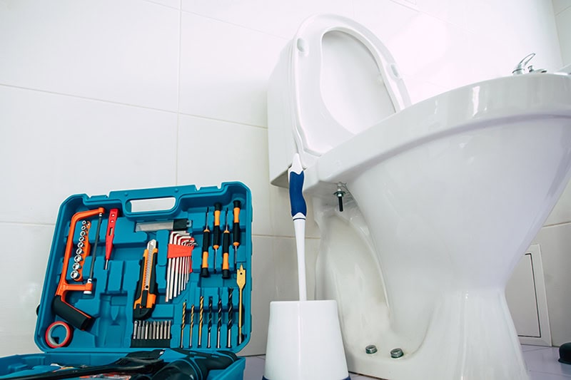 How to Unclog Your Slow-Draining Toilet in Egg Harbor Township. Photo of plumbing tools next to a toilet.